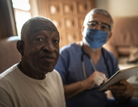 Elderly patient with male nurse in mask