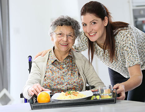 Elderly woman smiling with young woman over breakfast